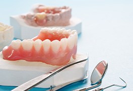 a plaster mold of a mouth with a denture sitting on top of it and dental instruments next to it