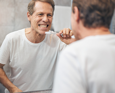 Man brushing his teeth in a mirror