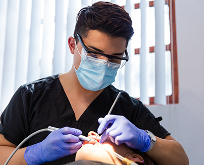 Dentist with mask performing oral cancer screening