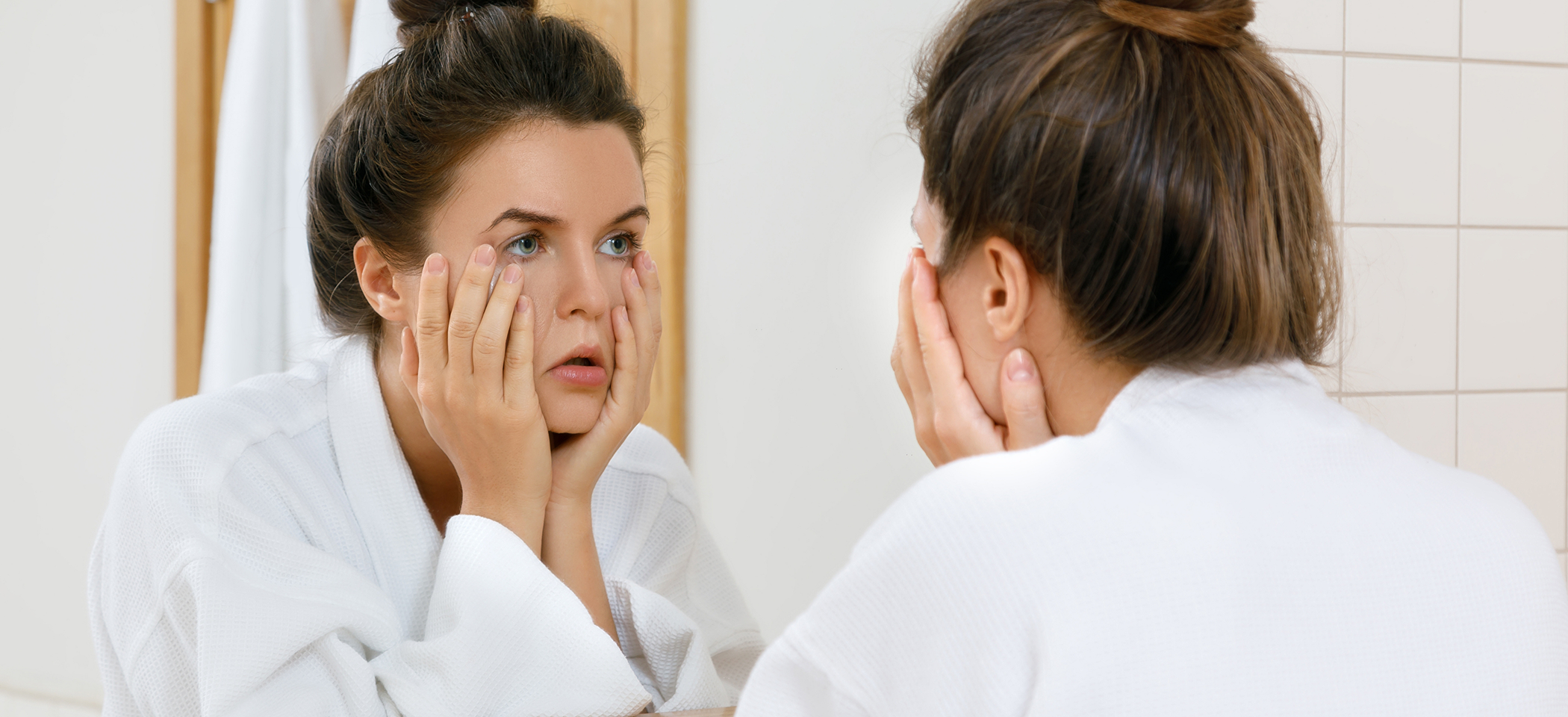 Woman looking in mirror pulling on face