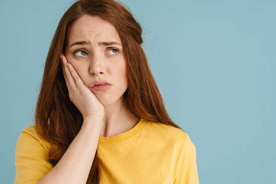 person holding their painful tooth